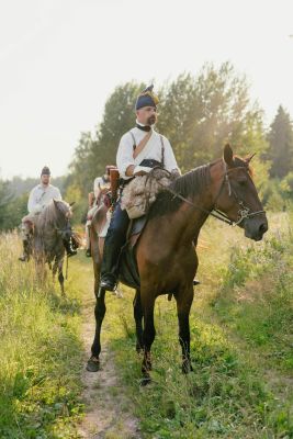 Historical reenactment of soldiers on horseback in a grassy field with vintage uniforms.